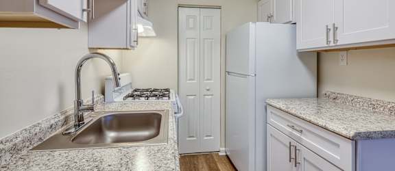 a kitchen with white cabinets and a sink and a refrigerator at Gates of West Bay in Norfolk, VA
