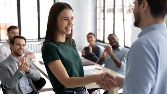 a woman shaking hands with a man in front of a group of people