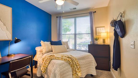 A bedroom with a bed, nightstand, and chair.
