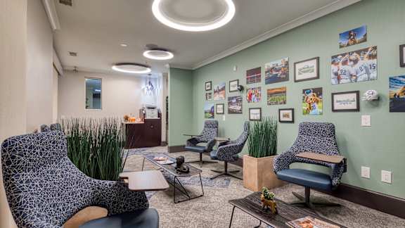 a living room with chairs and a table and a wall with pictures at Proximity at ODU, Norfolk, Virginia