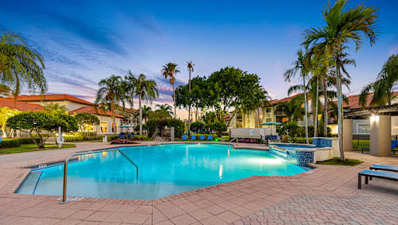 A swimming pool surrounded by palm trees and benches.