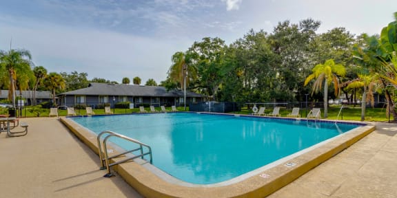 a large swimming pool with buildings in the background and trees