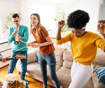 A group of friends are playing music and dancing together in a living room.