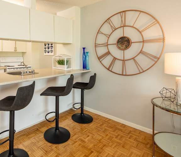 A kitchen with a bar and three stools.