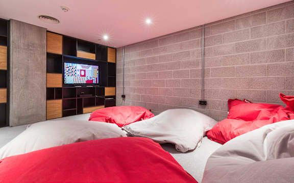 A bed with red pillows and a television in the corner at Beton Apartments, Wembley, HA9 0SL