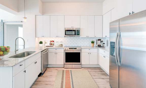 a white kitchen with stainless steel appliances and white cabinets