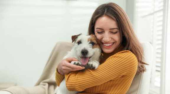 a woman holding a small dog on a couch