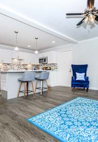 a living room with a kitchen and a ceiling fan