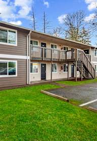 A two-story apartment building with a parking lot in front.