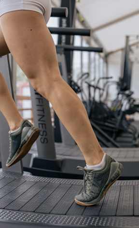 A woman is running on a treadmill in a gym.