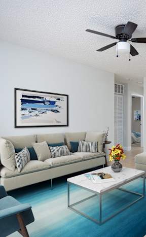 a living room with a couch and a coffee table and a ceiling fan