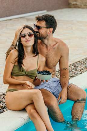 A man and woman sitting by a pool.