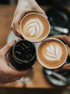 Three hands holding cups of coffee with latte art on top.at Alante Homes at Spring Run, Idaho