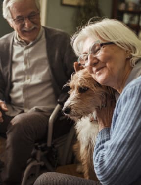 an older couple sitting in a wheelchair with their dog