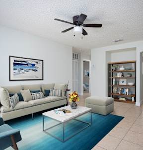 a living room with a couch and a coffee table and a ceiling fan