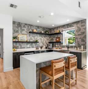 A kitchen with a white island and wooden chairs.
