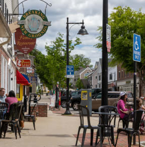 people sitting at tables outside a restaurant on a city street
