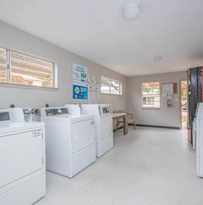 A laundry room with washers and dryers and a Coca-Cola fridge.