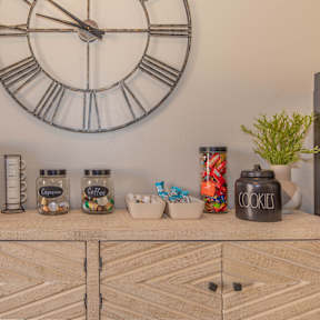 A coffee maker and a jar of cookies are on a wooden shelf.