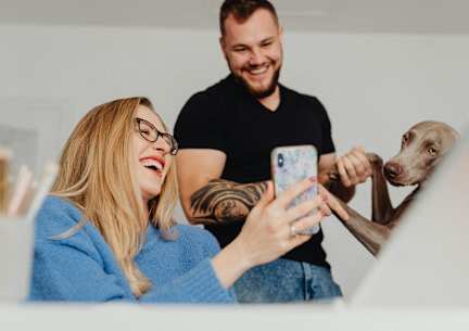 a man and woman with a dog looking at a cell phone