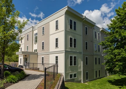 a large apartment building with green grass and trees in front of it