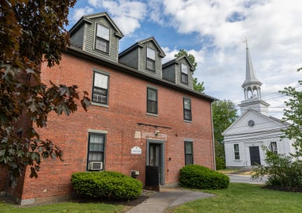a brick building with a white church steeple in the background