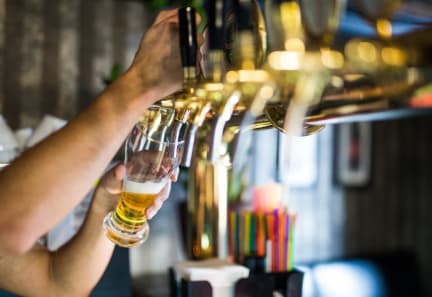 a person pouring a glass of beer in a bar