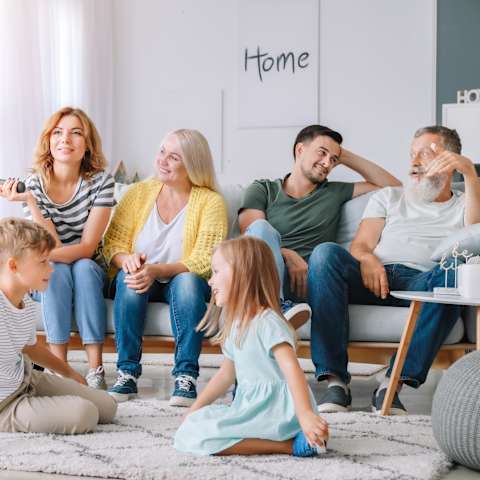 A family of six is sitting on the floor in their living room.
