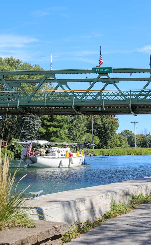 A green bridge over a body of water with boats underneath.