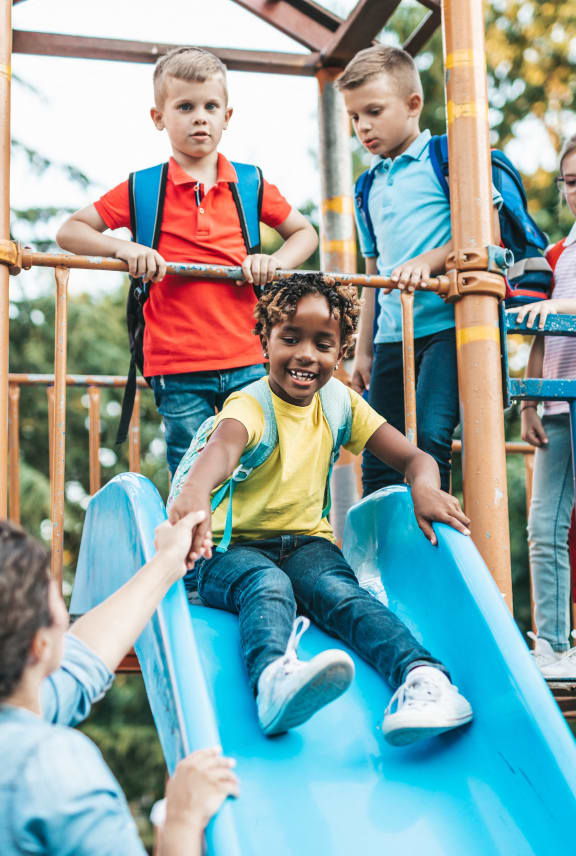 a group of children playing on a slide on a playground