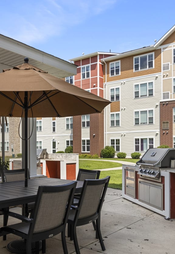 a patio with an umbrella and a table with chairs and a grill