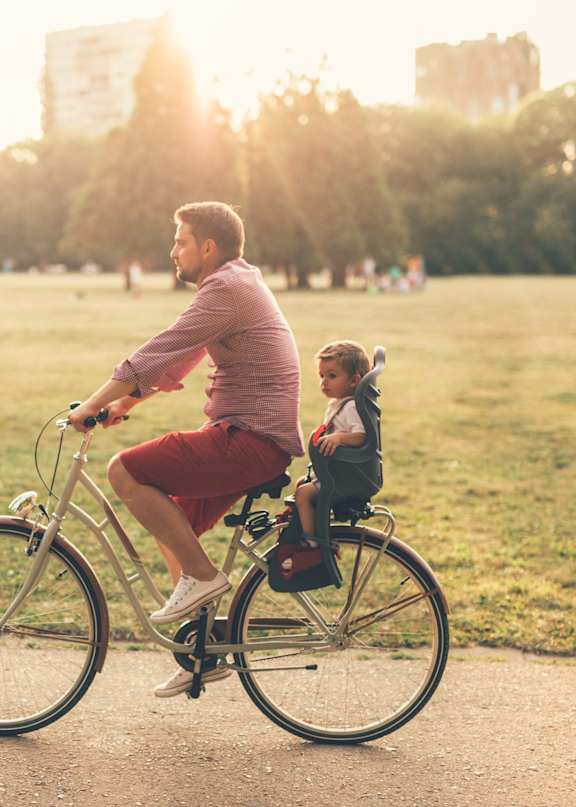 A man and a child are riding a bicycle in a park.