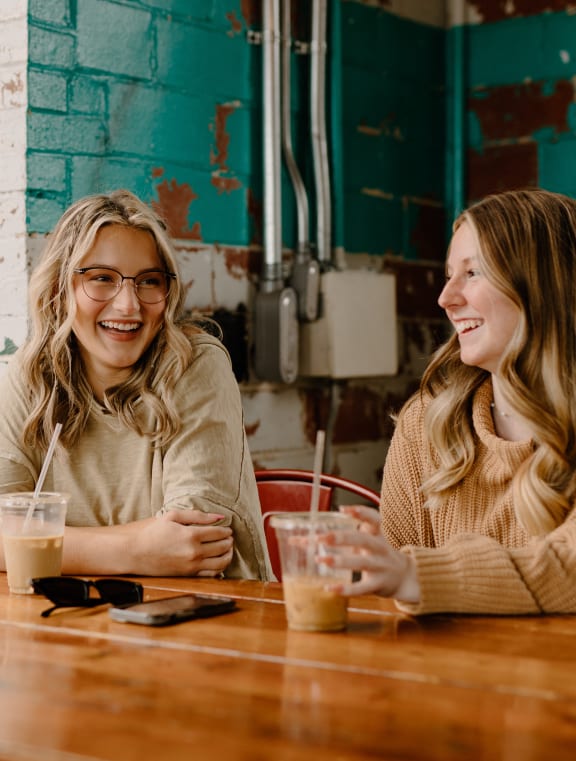 two women sitting at a table with drinks