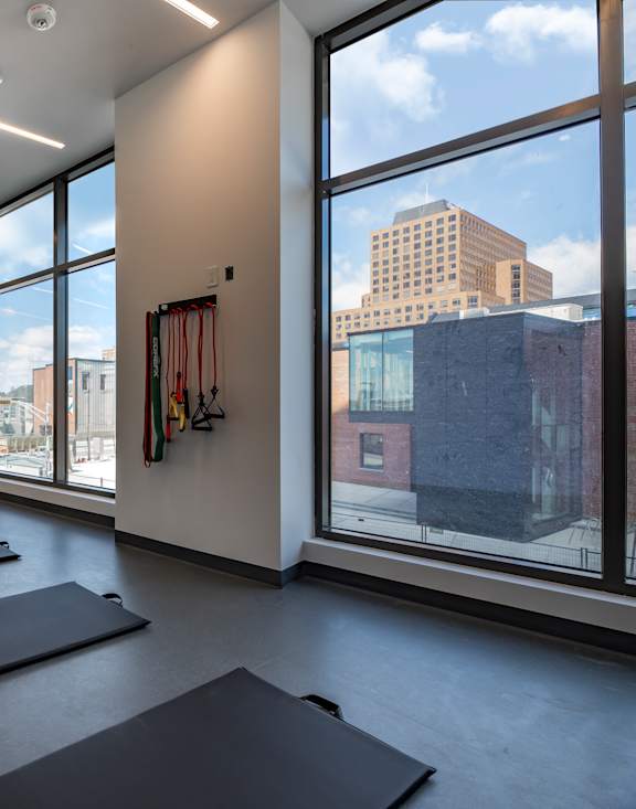 A yoga studio with mats on the floor and a view of the city outside the windows.