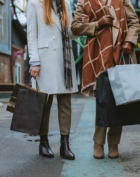Two women walking down the street carrying shopping bags.