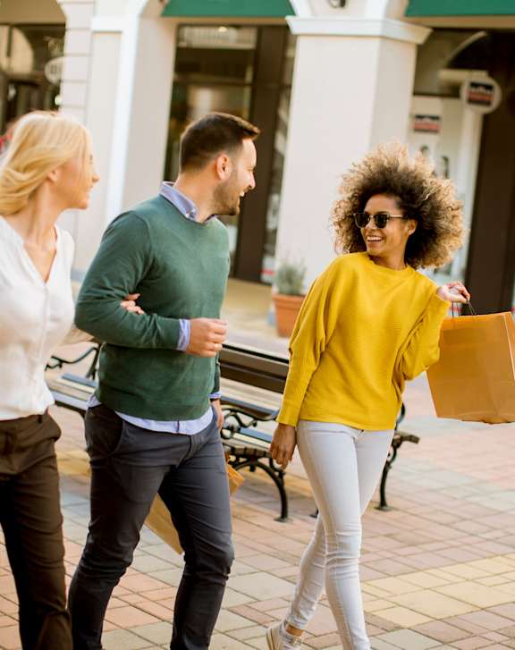 Three people walking in a shopping area.