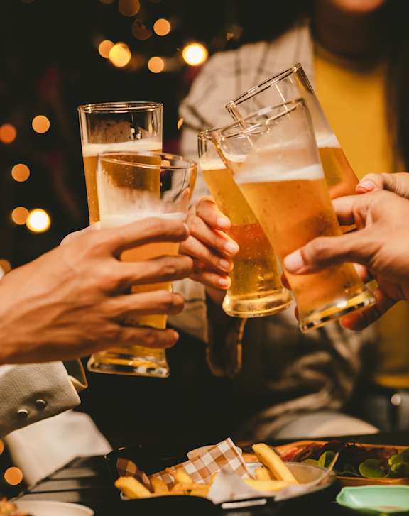 A group of people toasting with beer glasses at a table.