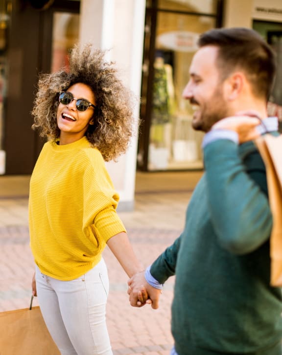 a man and woman walking down the street with shopping bags