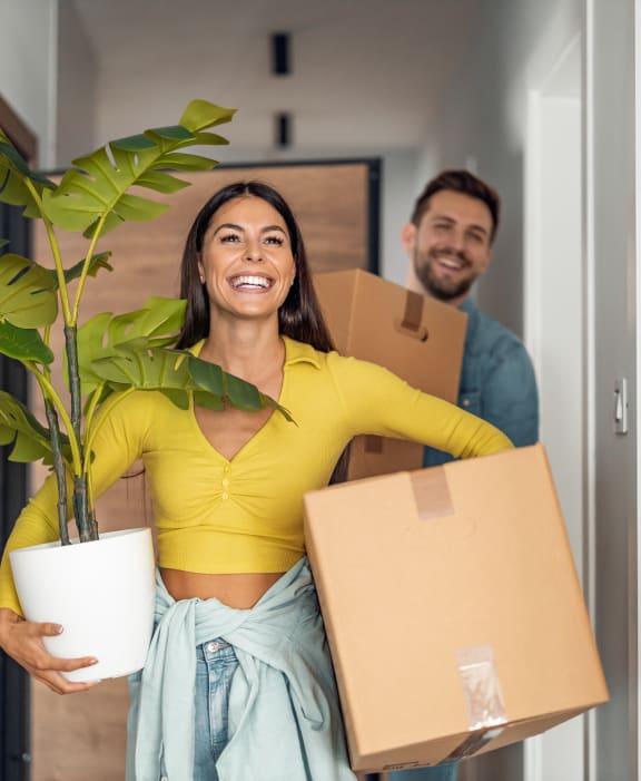 a man and a woman holding boxes and a plant