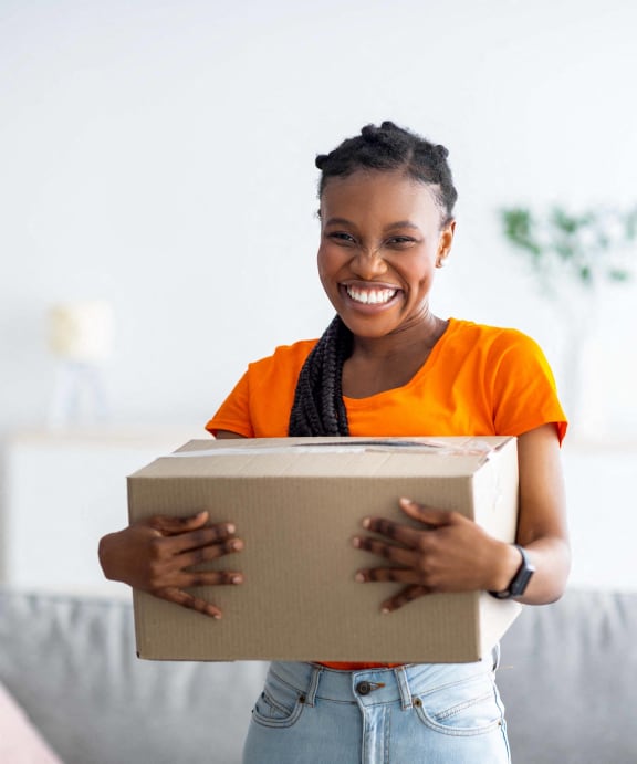 smiling woman holding a box in her living room