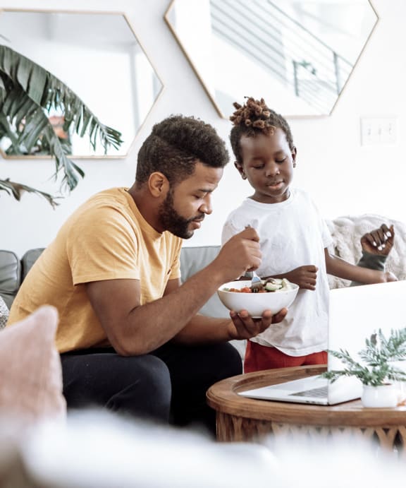a family sitting in a living room eating food and watching a television