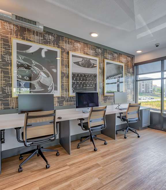 A modern office space with a long table and chairs, a patterned wall, and a view of the outdoors.