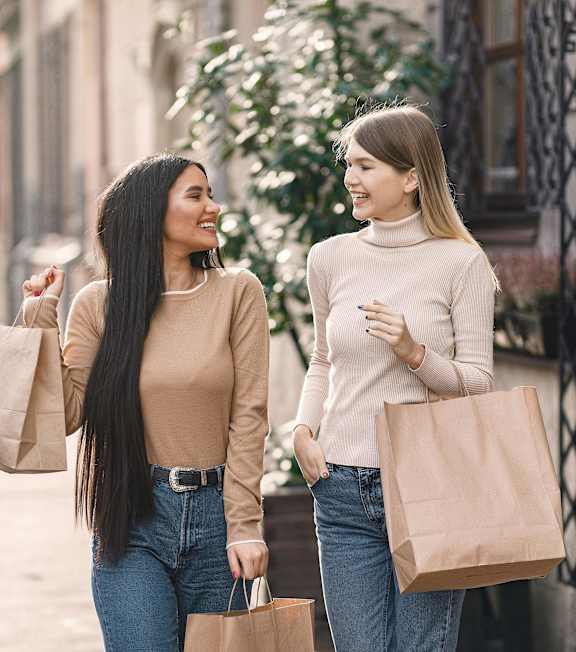 Two women walking down a street with shopping bags at Woodbriar Management in Georgia, 30084