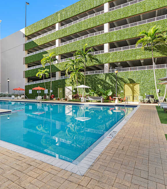 A swimming pool surrounded by a tiled walkway and lounge chairs.