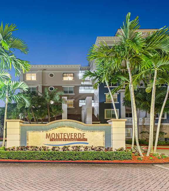 The image shows a sign that reads "MONTEVERDE" in front of a building with palm trees.