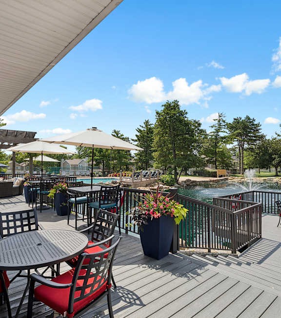A patio with a table and chairs overlooking a pool.