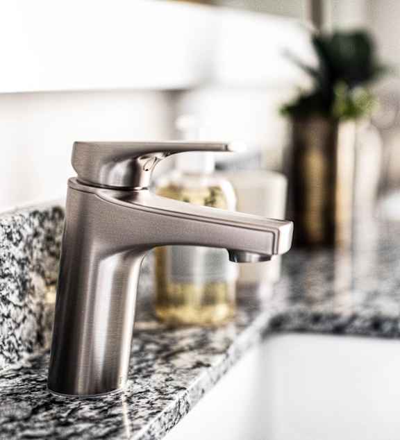 A modern bathroom sink with a silver faucet and a marble countertop.