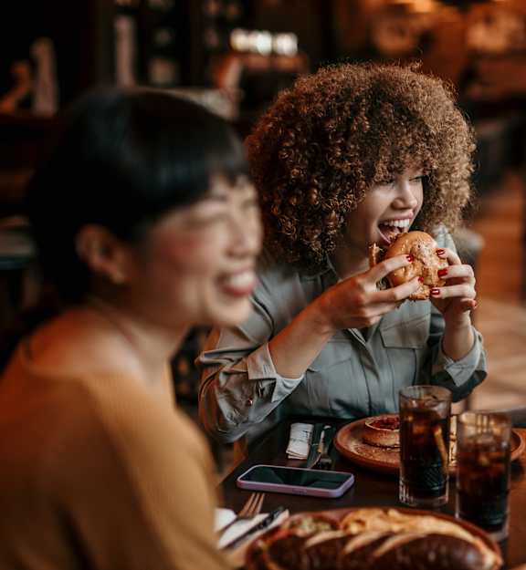 Three people eating pizza at a table.