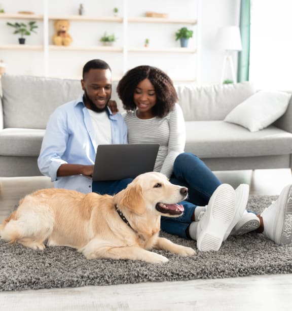 a couple sitting on the floor with their dog using a laptop computer at 44 West Luxury Living, Valley Park, Missouri