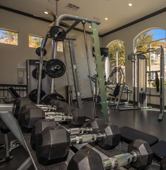 A gym with a variety of equipment including dumbbells, weight machines, and benches.